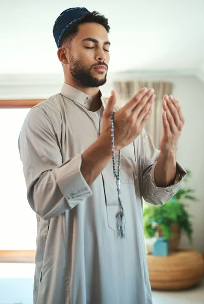 祈りは聞かない。それは魂の憧れです。自宅のラウンジで祈っている若いイスラム教徒の男のショット. — ストック写真