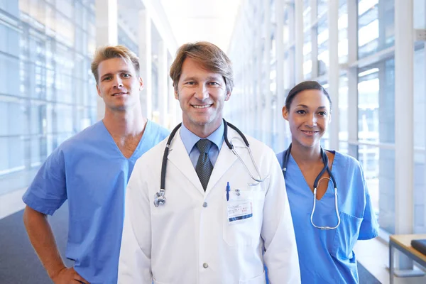 Estás en buenas manos. Un equipo médico de pie en el pasillo del hospital. —  Fotos de Stock