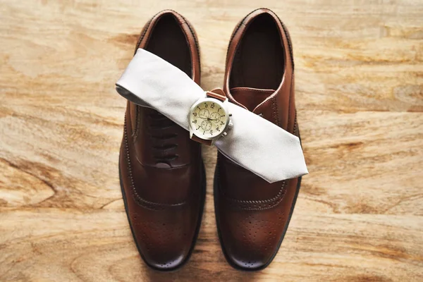 The three piece set every gentlemen has to have. Still life shot of a wristwatch and tie on top of formal shoes on a wooden surface. — Stock Photo, Image