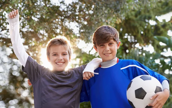 Pojkar kommer att vara pojkar. Skjuten av två unga pojkar som står utanför med en fotboll. — Stockfoto