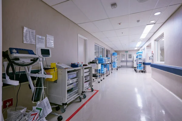 The hallway of healing. Shot of an empty passage way with medical equipment alongside the walls at a hospital. — Stock Photo, Image