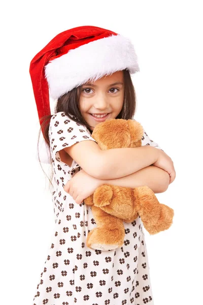 산타가뭘줬게 ?. 산타 모자를 쓰고 곰 인형을 안고 있는 사랑 스러운 어린 소녀의 사진. — 스톡 사진