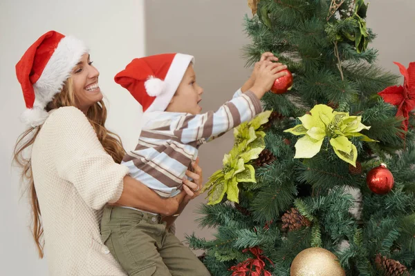 Csak egy kis segítség. Egy kisfiúról, aki karácsonyfát díszít az anyjával.. — Stock Fotó