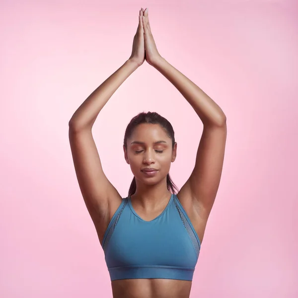 Finding her center. Cropped shot of an attractive and sporty young woman meditating in studio against a pink background. — Stock Photo, Image