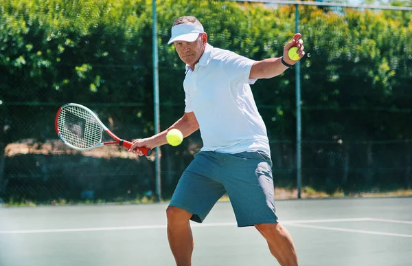 Zůstat zdravý je životní styl. Vystřižené záběr pohledný dospělý muž hraje tenis sám na kurtu během dne. — Stock fotografie