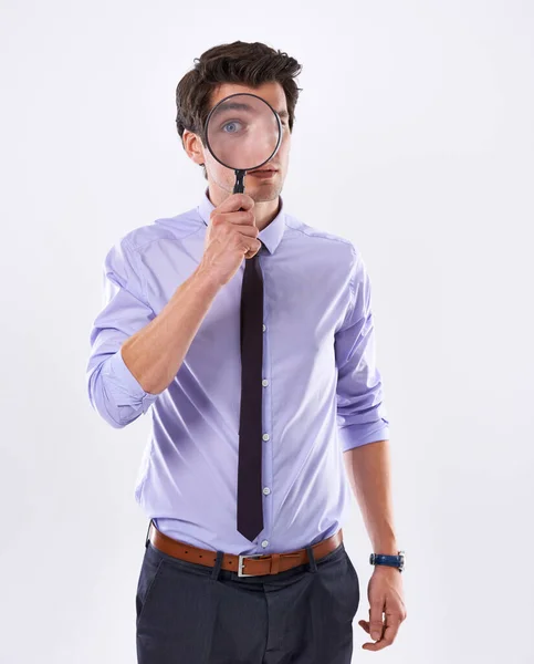 Time for your employee evaluation. Studio shot of a young businessman against a white background looking through a magnifying glass. — Stock Photo, Image