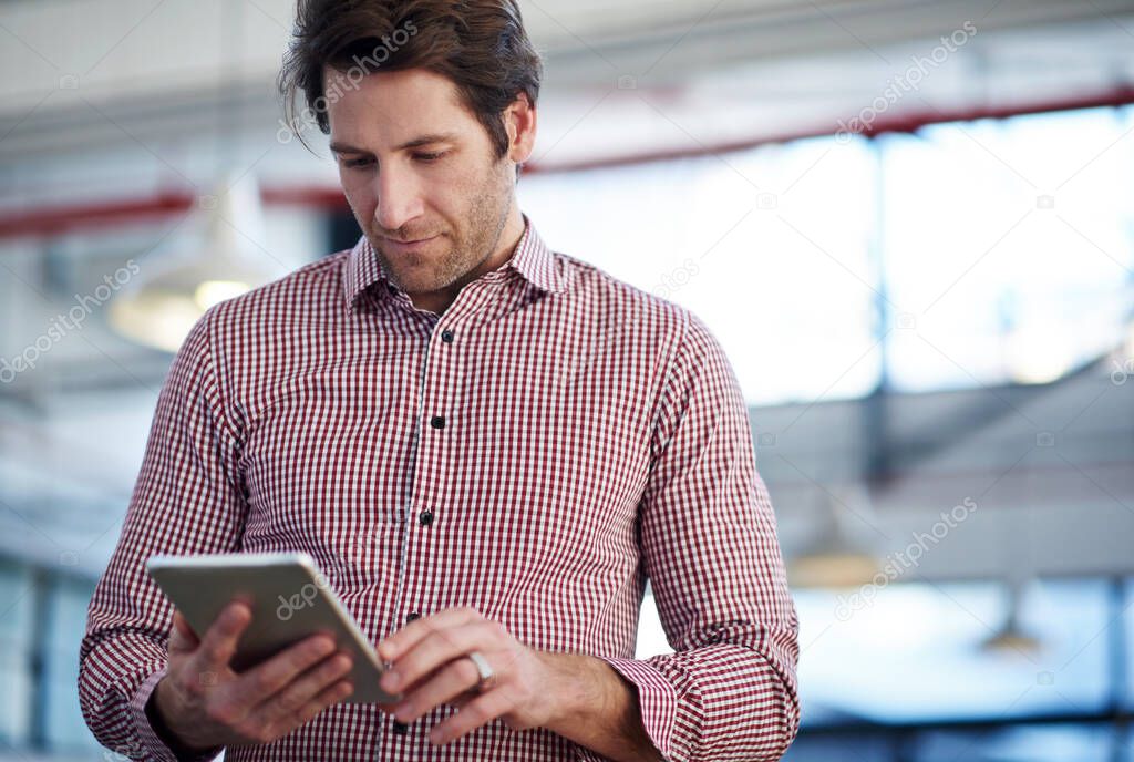 Future tech in todays business. Cropped image of a mature man using his digital tablet in an industrial office space.