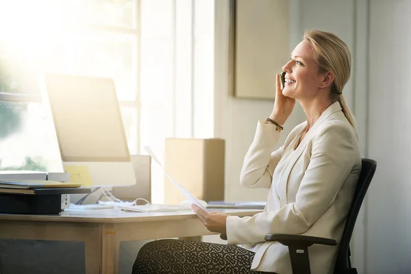 Комунікація є ключем до успіху. Постріл бізнес-леді розмовляє на мобільному телефоні, сидячи в її офісі . — стокове фото
