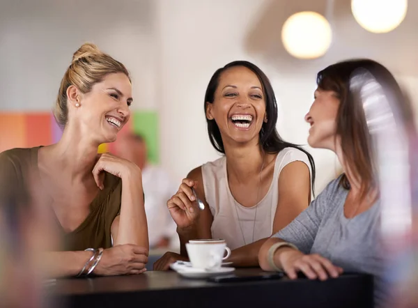 Ella sabe cómo hacer que todos sonrían. Foto de tres mujeres disfrutando de una conversación en un restaurante. — Foto de Stock