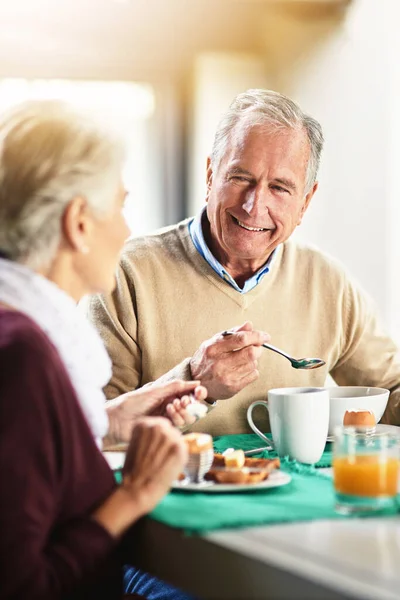 Semua kebahagiaan tergantung pada sarapan yang santai. Ditembak dari pasangan senior yang bahagia menikmati sarapan bersama di rumah. — Stok Foto