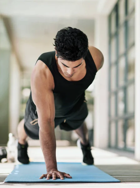 Cuando pienses en renunciar, recuerda por qué empezaste. Fotografía de un joven haciendo flexiones durante su entrenamiento en casa. —  Fotos de Stock