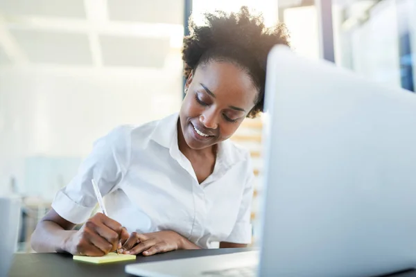 Anotar algunas ideas de negocio innovadoras. Recorte de una joven empresaria escribiendo notas mientras trabajaba en un ordenador portátil en una oficina moderna. — Foto de Stock