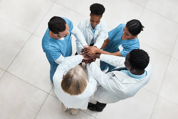 Promuovere il lavoro di squadra per migliorare i risultati dei pazienti. Colpo ad angolo alto di un gruppo di medici che si uniscono le mani in un ammasso. — Foto Stock