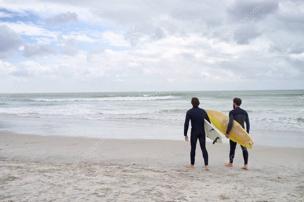 Surfing with my best mate. Two young surfers on the beach.