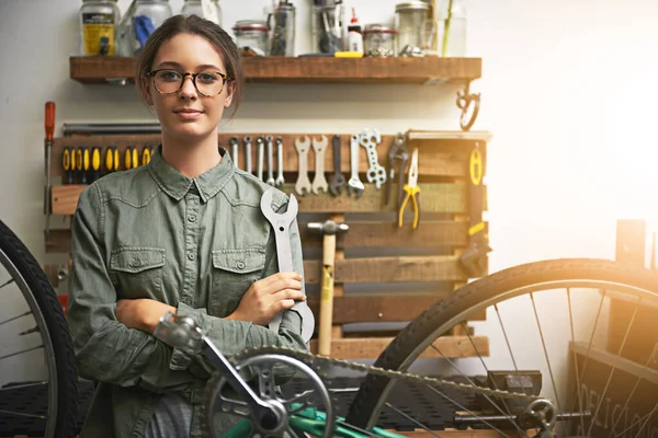 Ας πάρει το ποδήλατό σας πίσω στο ολοκαίνουργιο και πάλι. Πορτρέτο μιας νεαρής γυναίκας με αυτοπεποίθηση που εργάζεται σε ένα κατάστημα επισκευής ποδηλάτων. — Φωτογραφία Αρχείου
