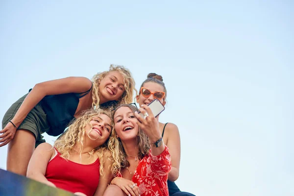 Het draait allemaal om de hoek. Low angle shot van een groep aantrekkelijke jonge vriendinnen nemen selfies in de stad. — Stockfoto