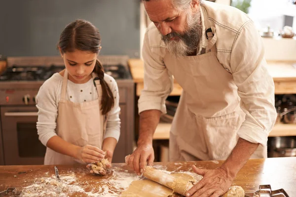 彼らはベーキングについて真剣に考えている。台所で一緒にパンを焼く女の子と彼女の祖父のショット. — ストック写真