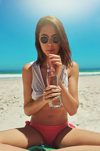 Sippin på något kallt. Porträtt av en sexig ung kvinna som njuter av en drink på stranden. — Stockfoto
