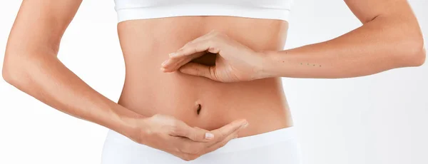 Un intestino sano requiere una dieta equilibrada. Foto de una mujer sosteniendo sus manos en forma circular frente a su estómago contra un fondo de estudio. — Foto de Stock