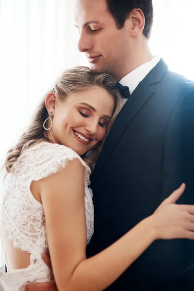 Ты обнял меня, и я был дома. Обрезанный снимок счастливой молодой пары, стоящей в помещении и нежно обнимающей друг друга после свадьбы. — стоковое фото