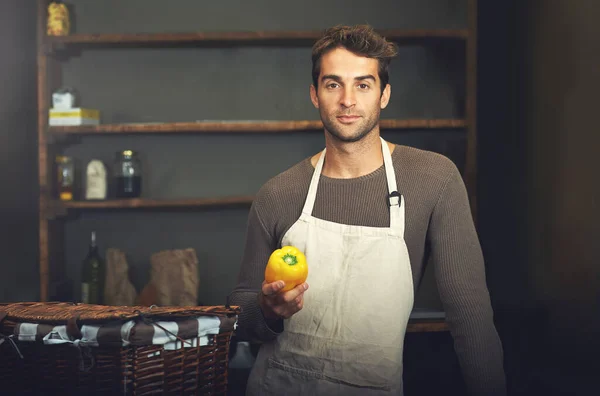 É um profissional na cozinha. Tiro de um jovem segurando uma pimenta amarela em sua cozinha. — Fotografia de Stock