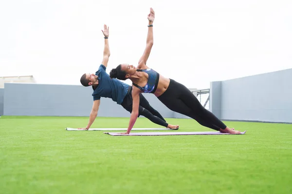 Залишайтеся придатними, щоб бути сильними. Знімок молодого чоловіка і жінки, що практикує йогу разом на відкритому повітрі . — стокове фото