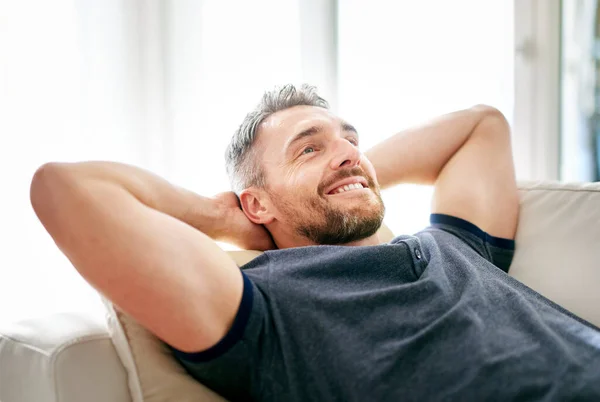 Enjoying his day off. Shot of a handsome mature man relaxing on the sofa at home. — Stock Photo, Image