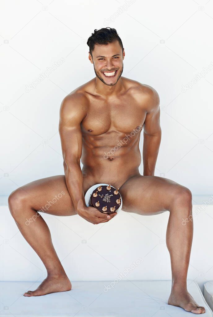 I wore my birthday suit to match the occasion. Shot of a handsome young man posing nude with a chocolate cake.