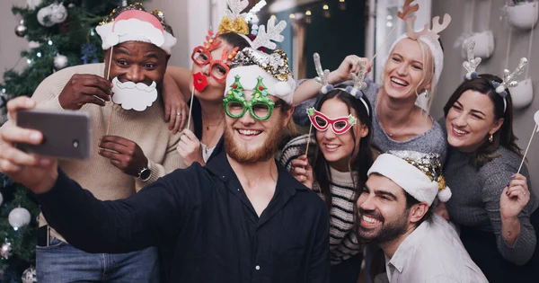 Çılgın arkadaşlar eğlenceli anılar yaratır. Komik şapkalar takan ve Noel partisinde selfie çeken bir grup genç arkadaşın fotoğrafı.. — Stok fotoğraf