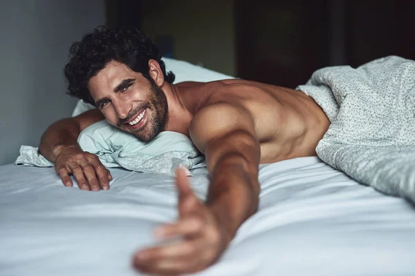 Viens te joindre à moi. Coupé coup d'un beau jeune homme torse nu couché dans le lit à la maison. — Photo