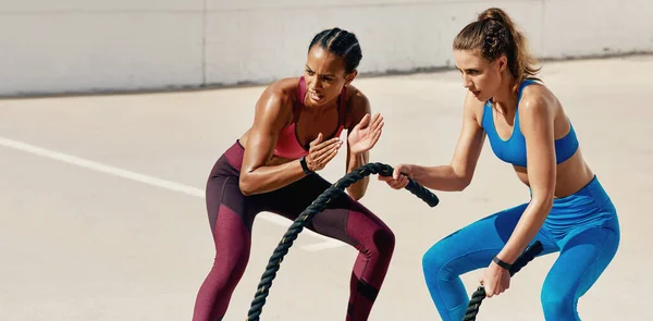 Твоє досягнення варте цих важких уроків. Знімок спортивної молодої жінки, яка тренує важку мотузку зі своїм тренером . — стокове фото