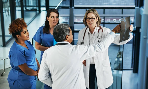 환자의 건강은 팀의 노력입니다. 병원에서 엑스레이 결과에 대해 논의하고 있는 의사들의 팀이 찍은 사진. — 스톡 사진