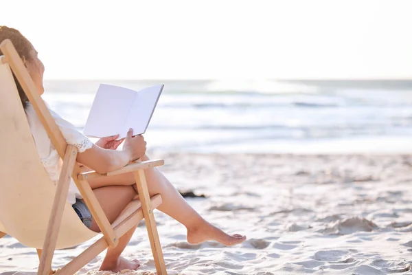 Inget går upp mot havet och en bra bok. Skjuten av en oigenkännlig kvinna läser en bok på stranden. — Stockfoto