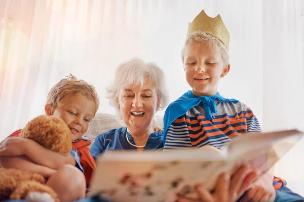 Abuela está leyendo nuestra historia favorita de nuevo. Un disparo de una mujer mayor que pasa tiempo marchitando a sus nietos. — Foto de Stock