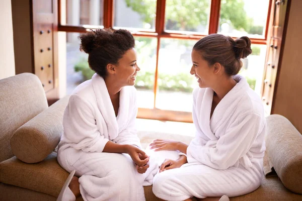 Chillen im Wellnessbereich. Aufnahme von zwei Freunden in Bademänteln, die in einem Wellnessbereich reden und lachen. — Stockfoto
