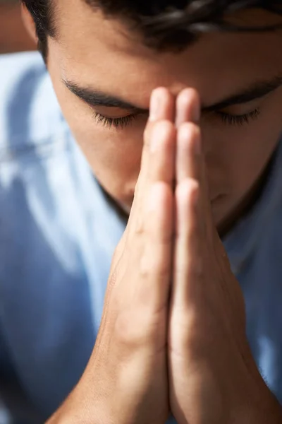 Hoping and praying. Closeup of a young man praying with his hands together. — Stock Photo, Image
