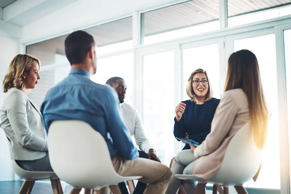 Revisando su plan. Recorte de un grupo de colegas corporativos reunidos en su oficina. —  Fotos de Stock