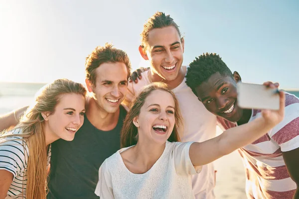 Die sommerliche Jahreszeit mit einem Selfie feiern. Aufnahme einer glücklichen Gruppe von Freunden, die gemeinsam Selfies am Strand machen. — Stockfoto