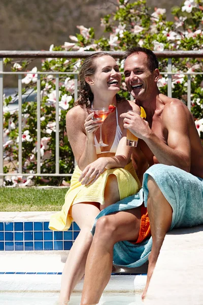 Vietetään joka päivä näin. Rakastava pari nauraa istuessaan ulkona uima-altaalla ja juoden cocktaileja.. — kuvapankkivalokuva