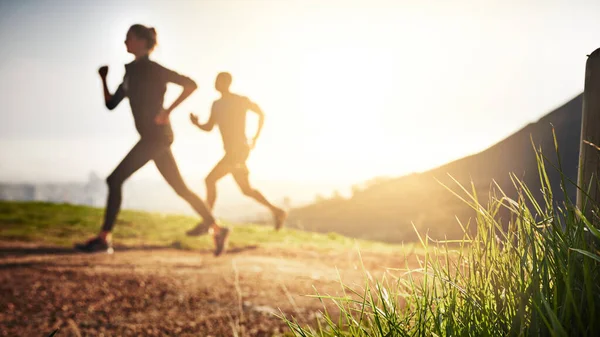 Du har förmågan att nå högre höjder. Skjuten av ett sportigt par som springer på en bergsväg. — Stockfoto