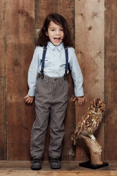 Zanechán v muzeu. Shot of a stylish young boy posing next to a plyffed owl. — Stock fotografie