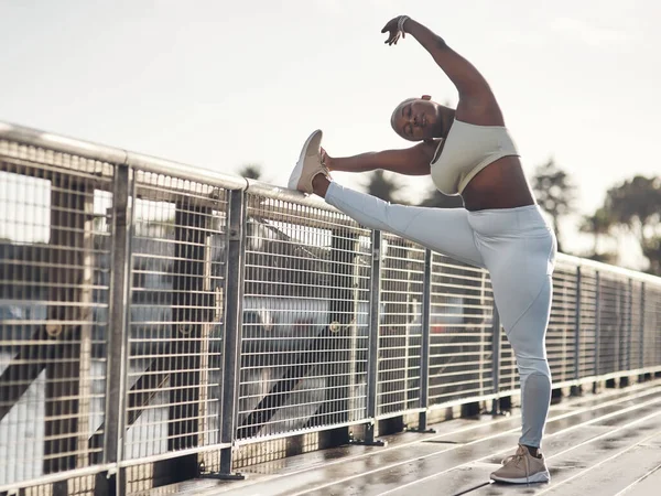 Stretch Its not optional. Shot of a young woman stretching on a footbridge. — Stock Photo, Image