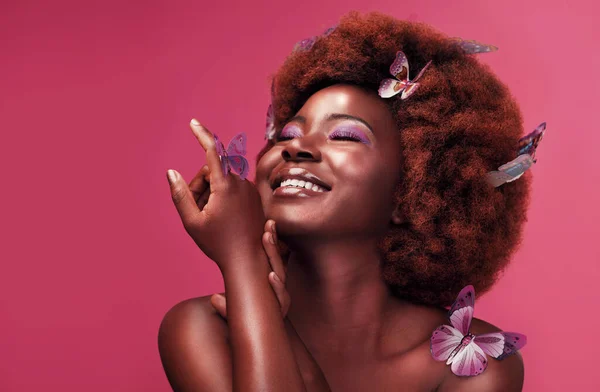 Las mariposas son bonitas, pero es más bonita. Foto de estudio de una hermosa joven sonriendo mientras posaba con mariposas en el pelo sobre un fondo morado. — Foto de Stock