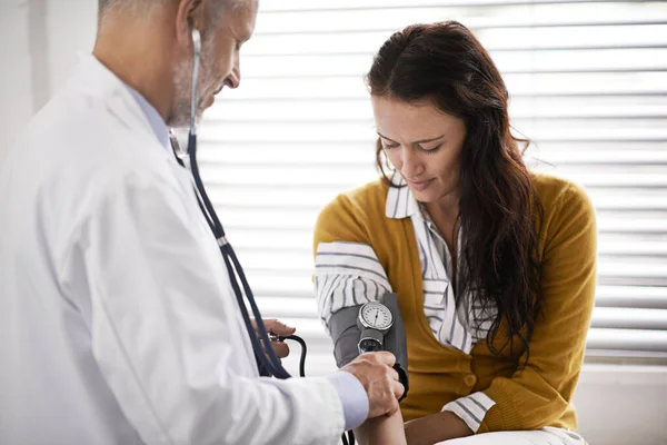 Aquí para su chequeo de rutina. Inyección recortada de un médico que revisa la presión arterial de un paciente. —  Fotos de Stock