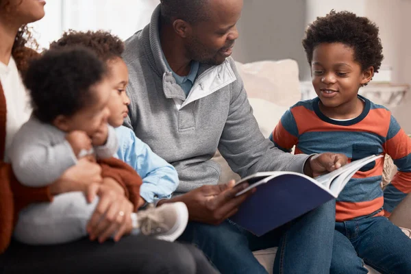 Tornou-se uma tradição em sua família para ler juntos. Tiro de um pai lendo um livro para sua família em casa. — Fotografia de Stock