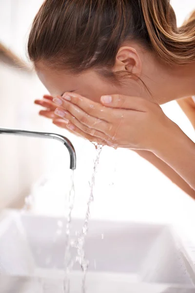 A gyönyörű bőr mosással kezdődik. Közelkép egy fiatal nőről, aki az arcát mossa a mosogatón.. — Stock Fotó