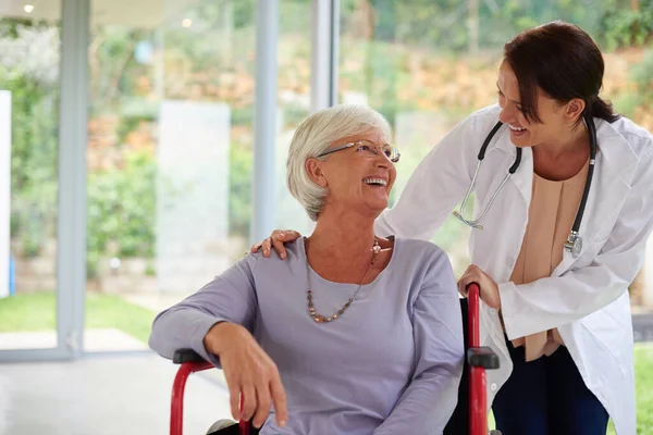 Dokter en patiëntenbinding. Shot van een gelukkige oudere vrouw in een rolstoel praten met haar arts. — Stockfoto