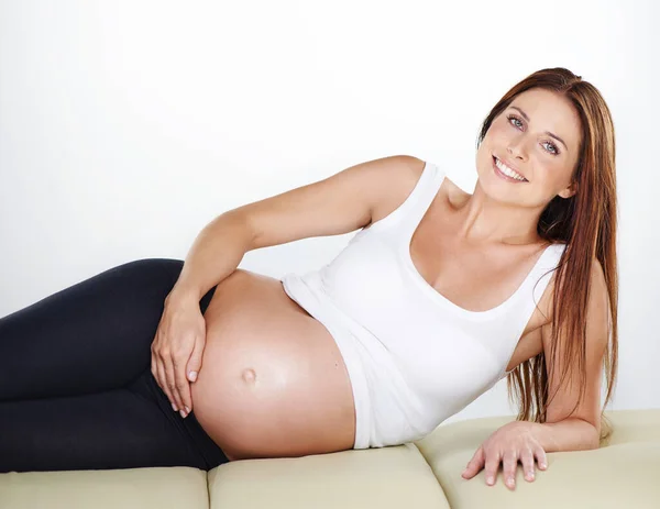 Ela tem aquele brilho de gravidez. Tiro cortado de uma mulher grávida segurando sua barriga enquanto relaxa. — Fotografia de Stock