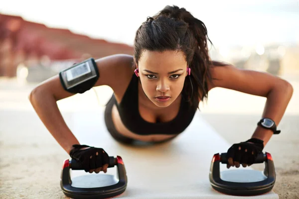 Ampli la spinta. Colpo di una giovane donna che si esercita utilizzando manopole push up. — Foto Stock