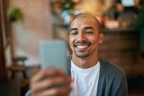 Estaré esperándote en el café. Cortada la foto de un joven enviando mensajes de texto en su celular en un café. —  Fotos de Stock